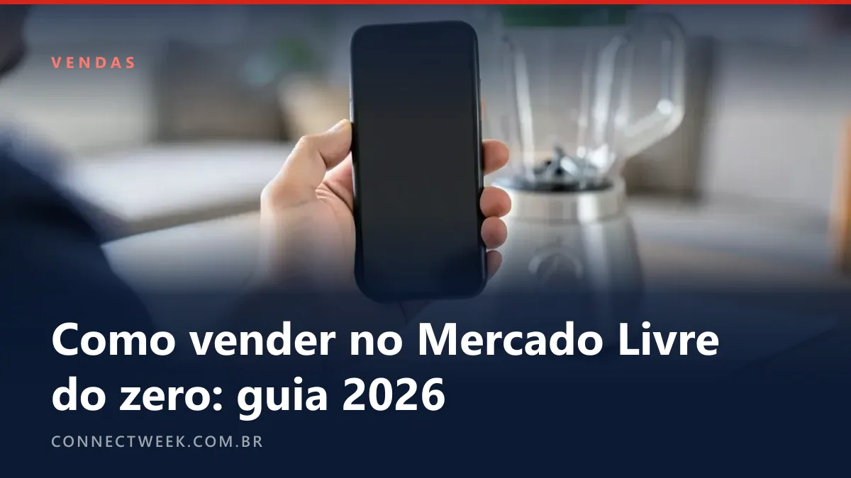 Mão segurando um celular diante de um liquidificador sem marca de tampa verde, apoiado sobre uma folha de papel branco numa mesa de casa