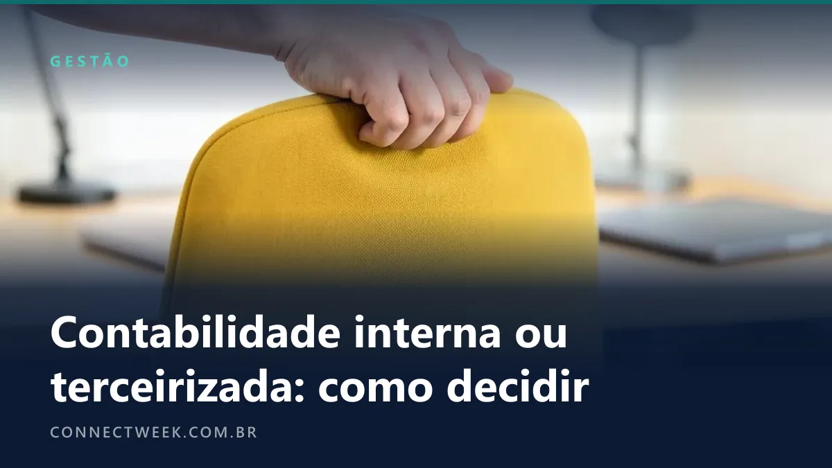 Mão puxando pelo encosto uma cadeira de escritório amarelo-mostarda vazia diante de uma mesa de trabalho arrumada