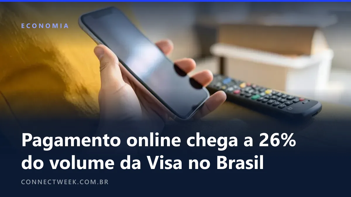 Mão segurando um celular de tela escura sobre o braço de um sofá mostarda, com um controle remoto ao lado e uma caixa de papelão desfocada ao fundo