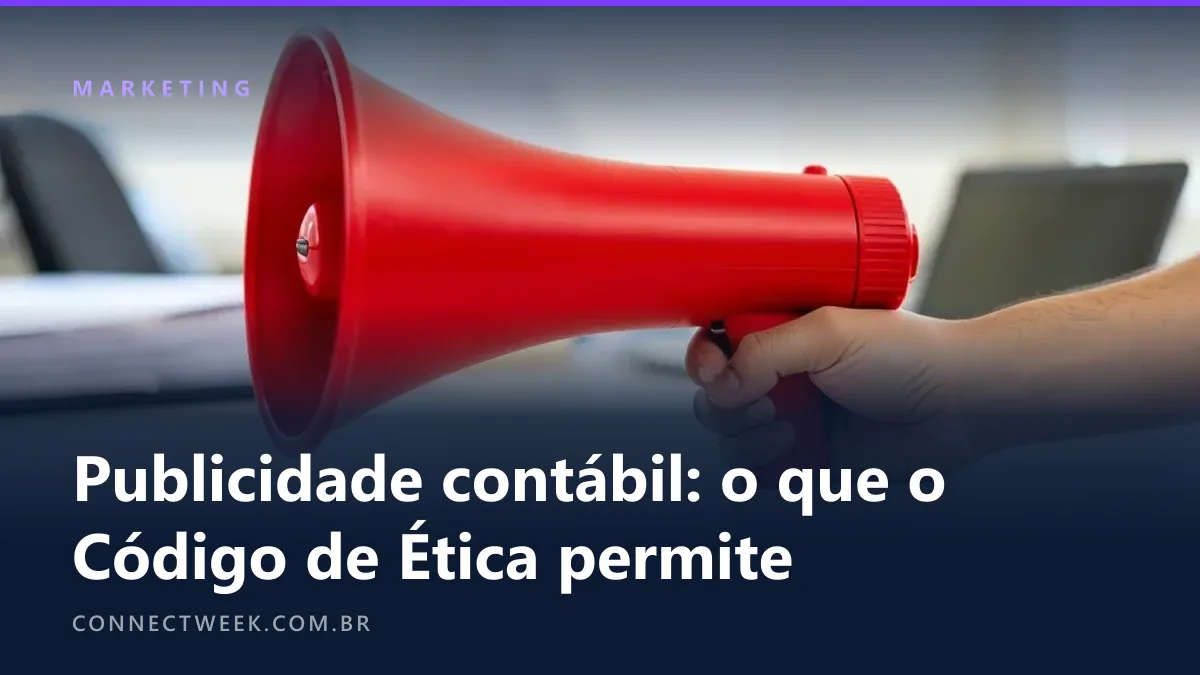 Mão segurando pela alça um megafone vermelho num escritório desfocado