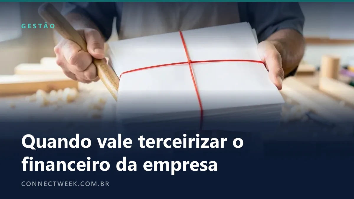 Marceneiro de avental segurando o cabo de uma ferramenta de madeira numa mão e, na outra, um maço de envelopes brancos preso por elástico vermelho, numa oficina