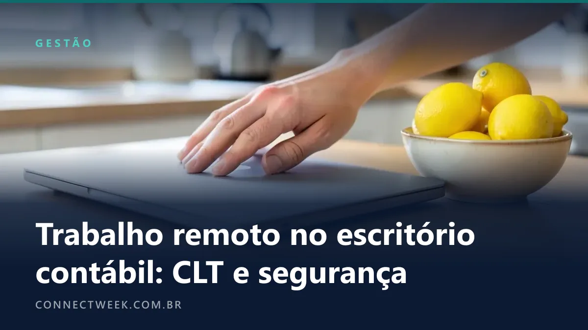 Mão pousando um notebook fechado de tampa lisa sobre uma mesa de cozinha, ao lado de uma fruteira com limões
